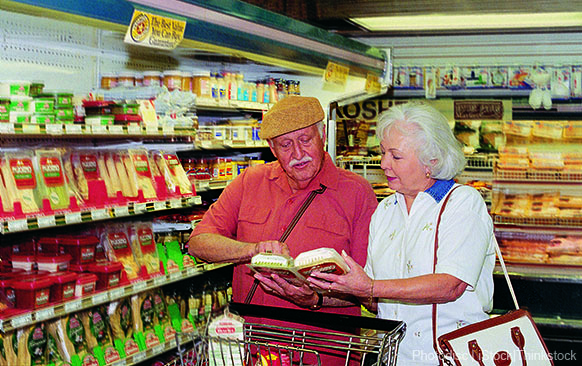 A photo shows an older couple grocery shopping and reading food labels