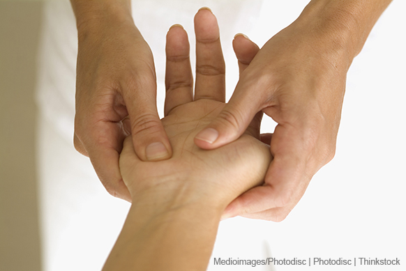 A photo shows a therapist using thumbs to apply acupressure on a patient's hand